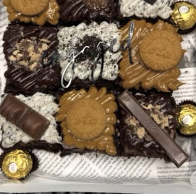 A box of brownies topped with Biscoff cookies, Kinder bars, Oreo crumbs and Ferrero Rocher